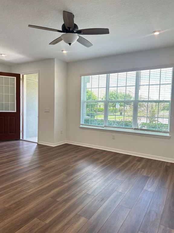 An empty room features wood-look flooring, a ceiling fan, and a large window — 9031 LEGADO DRIVE, WINDERMERE, FL