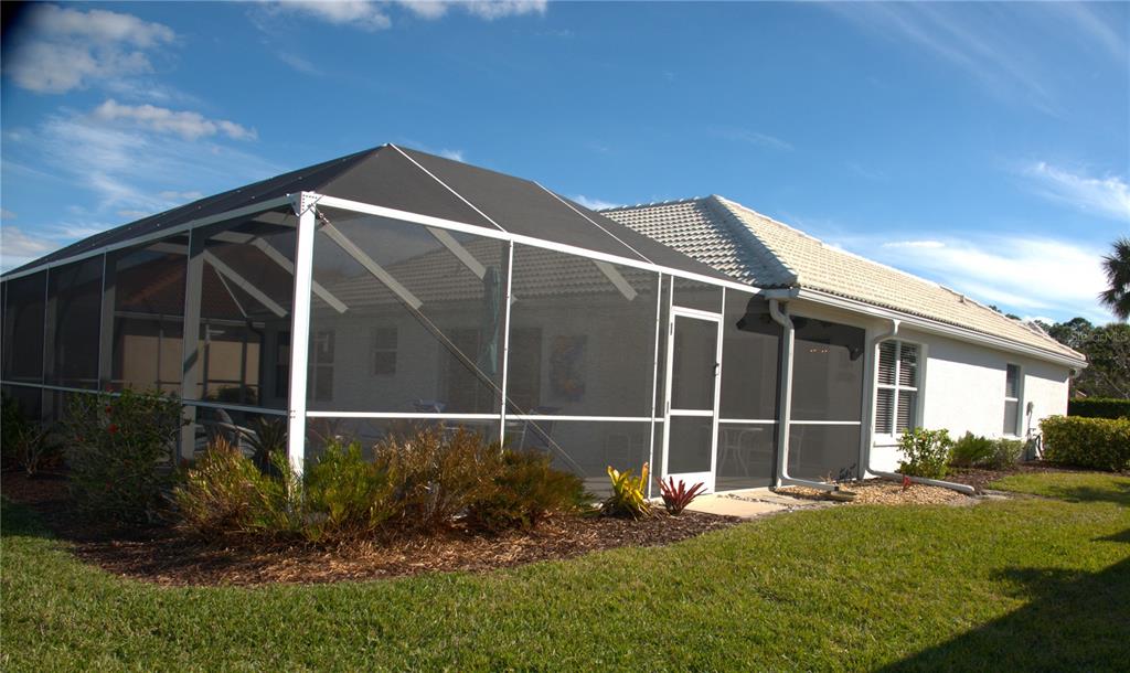 A white house with a screened-in pool enclosure and a tiled roof under a blue sky — 1303 ISLAMORADA BOULEVARD, PUNTA GORDA, FL