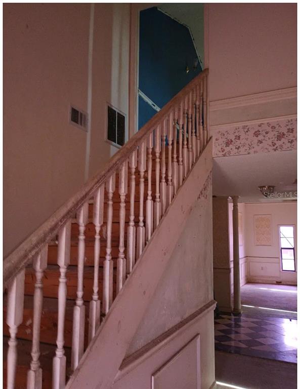 A wooden staircase with white balusters leads to an upper level in a residential interior — 1882 BANKS ROAD, LAKE WALES, FL