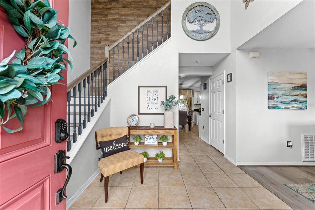 An entryway features a staircase with wood-look wall accents, a console table, and a chair — 1778 SUNSET RIDGE DRIVE, MASCOTTE, FL