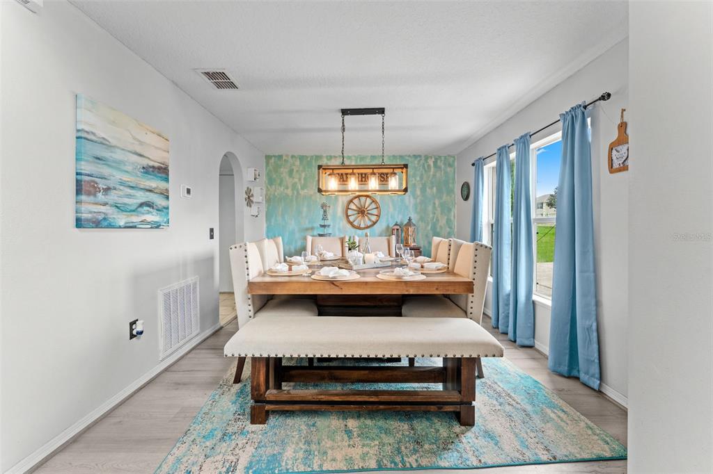 A dining room features a wooden table with a bench, upholstered chairs, and blue curtains — 1778 SUNSET RIDGE DRIVE, MASCOTTE, FL