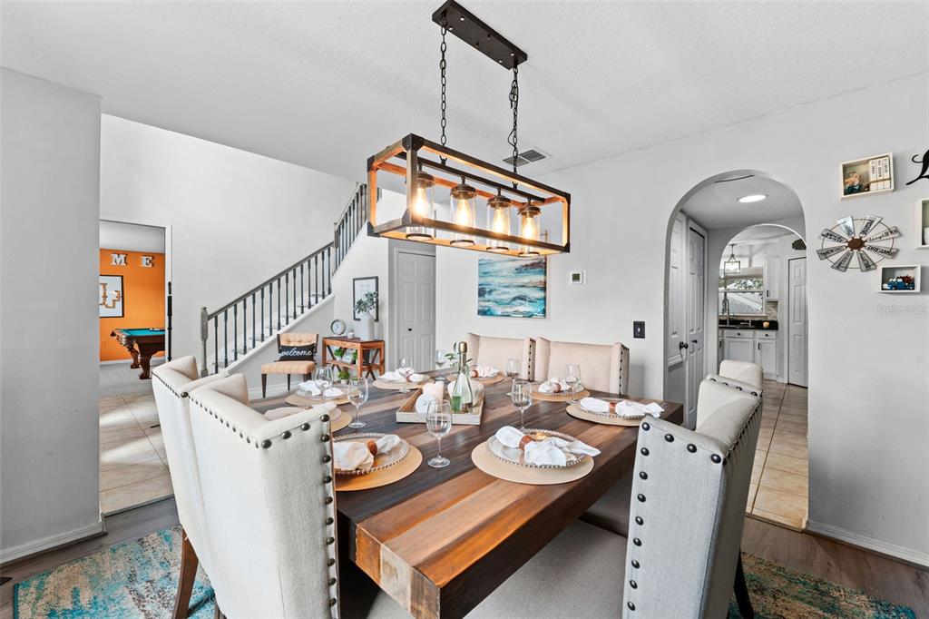 A dining room features a wooden table, upholstered chairs, and a rectangular pendant light fixture — 1778 SUNSET RIDGE DRIVE, MASCOTTE, FL