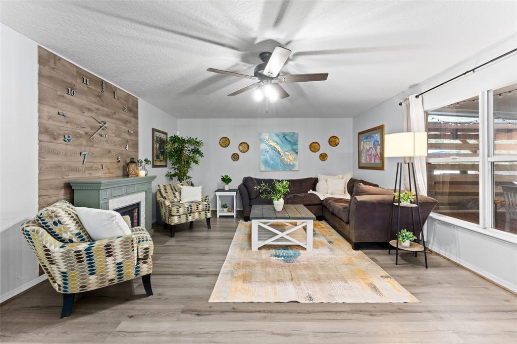 A living room features a wood-paneled accent wall with a clock, fireplace, and sectional sofa — 1778 SUNSET RIDGE DRIVE, MASCOTTE, FL