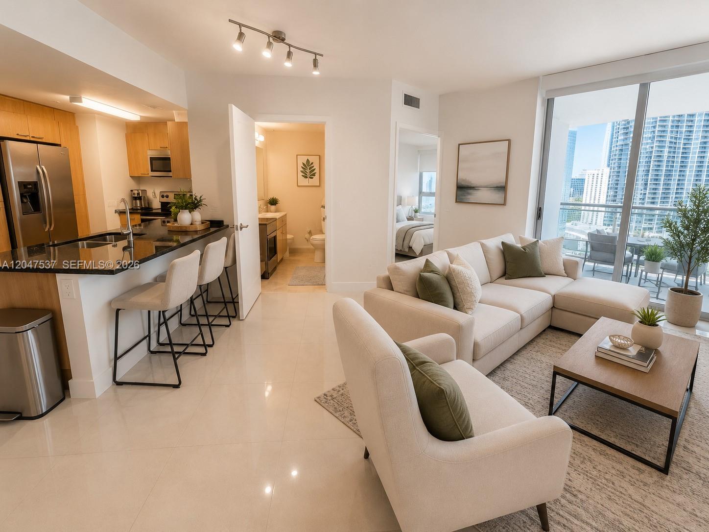 An open-concept living area features a kitchen with bar seating and a view of skyscrapers — 350 S Miami Ave # 3304, Miami FL 33130, MIAMI, FL