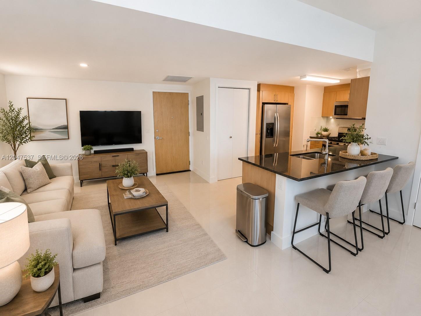 An open-concept living room and kitchen feature light wood cabinetry, stainless steel appliances, and tile flooring — 350 S Miami Ave # 3304, Miami FL 33130, MIAMI, FL
