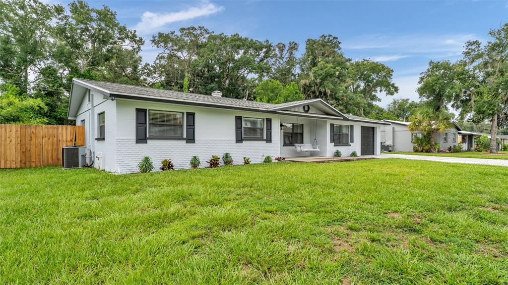 A single-story white brick house with black shutters and a front porch swing — 135 KENILWOOD LANE, LAKELAND, FL