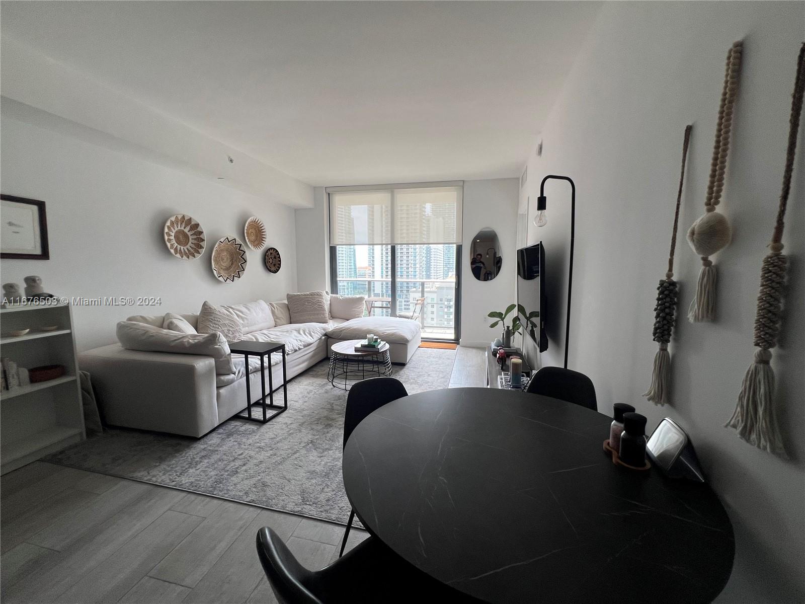A modern living room features a white sectional sofa, a round dining table, and city views — 55 SW 9th St # 1604, Miami FL 33130, MIAMI, FL