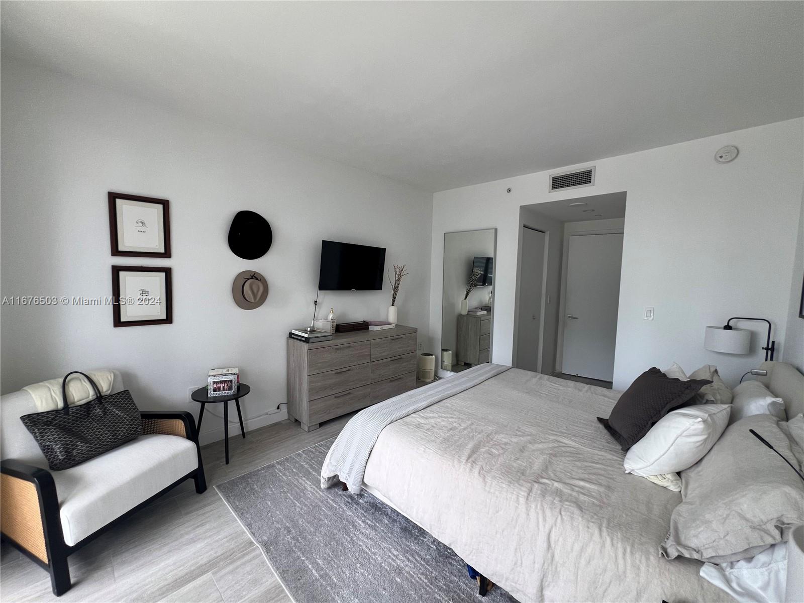 A bedroom features a bed, a dresser with a television, and a chair — 55 SW 9th St # 1604, Miami FL 33130, MIAMI, FL