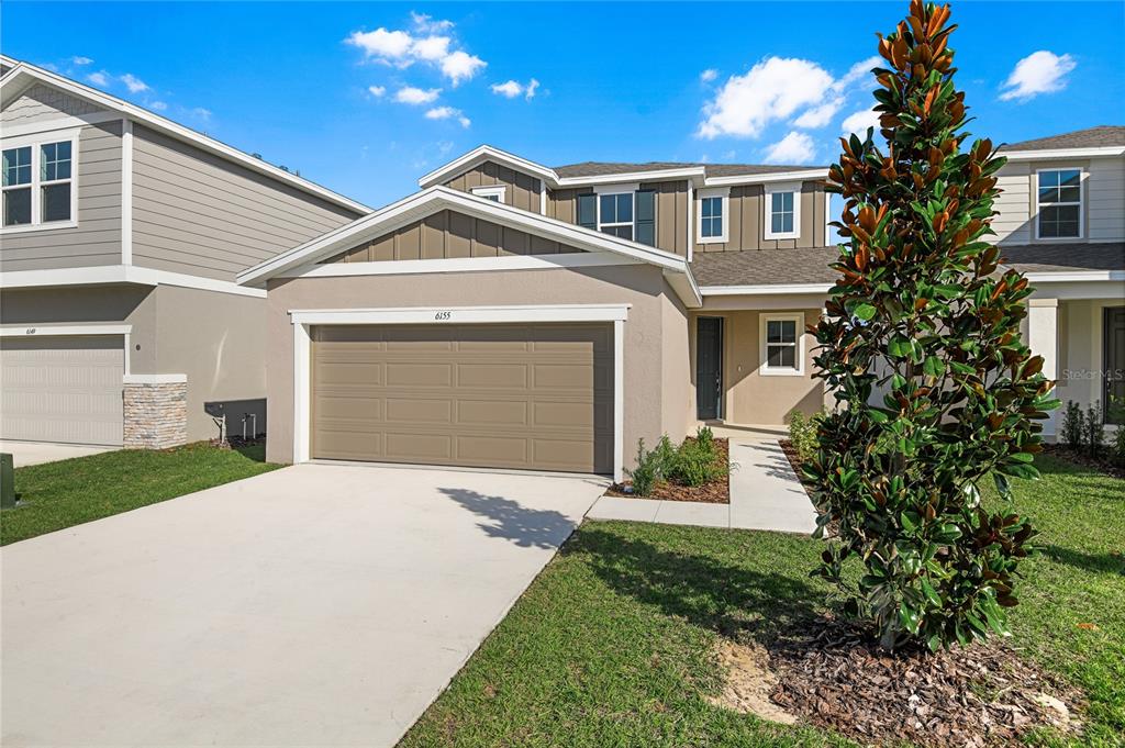 A two-story suburban house features a tan exterior, a two-car garage, and a front lawn — 6155 SW 64TH TERRACE, OCALA, FL