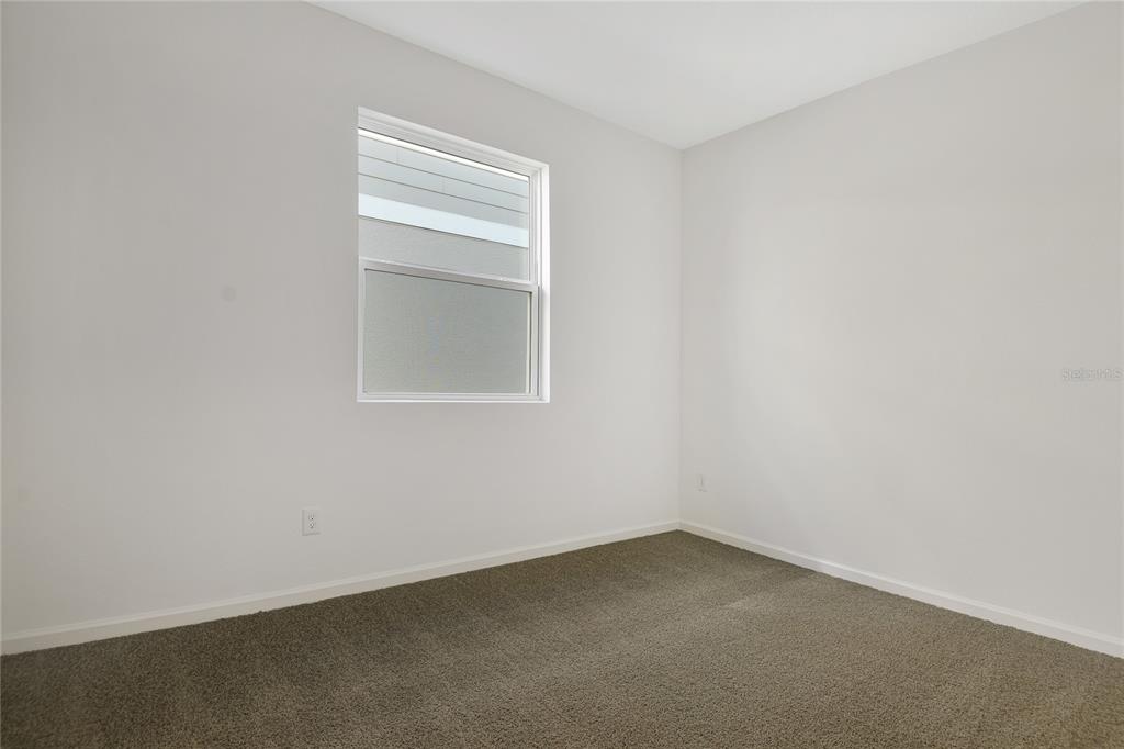 An empty bedroom features white walls, gray carpeting, and a single window — 6155 SW 64TH TERRACE, OCALA, FL