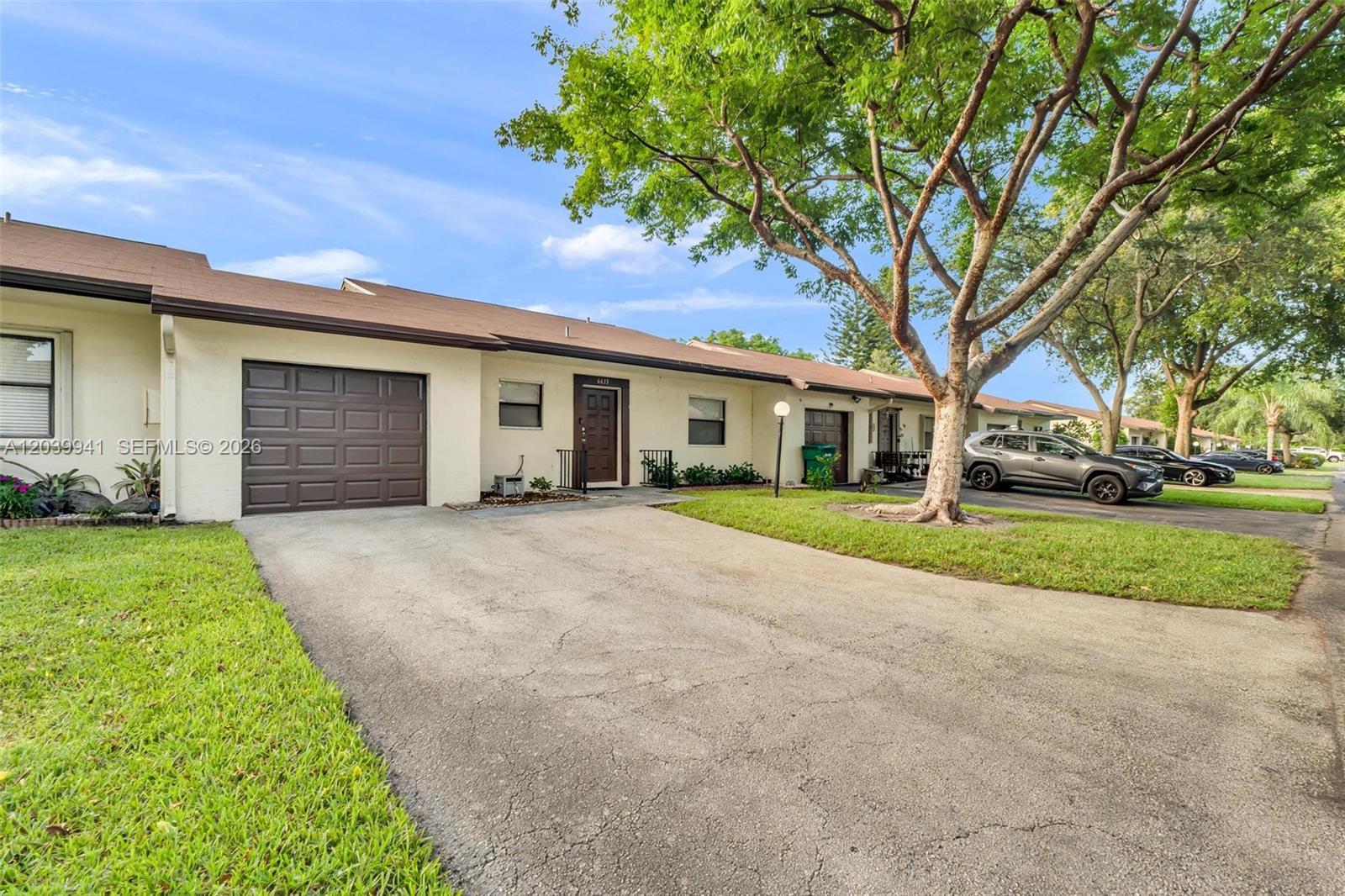 A single-story townhouse features a brown garage door, a front entrance, and a paved driveway — 6633 N Parkway Dr # 7, Margate FL 33068, MARGATE, FL