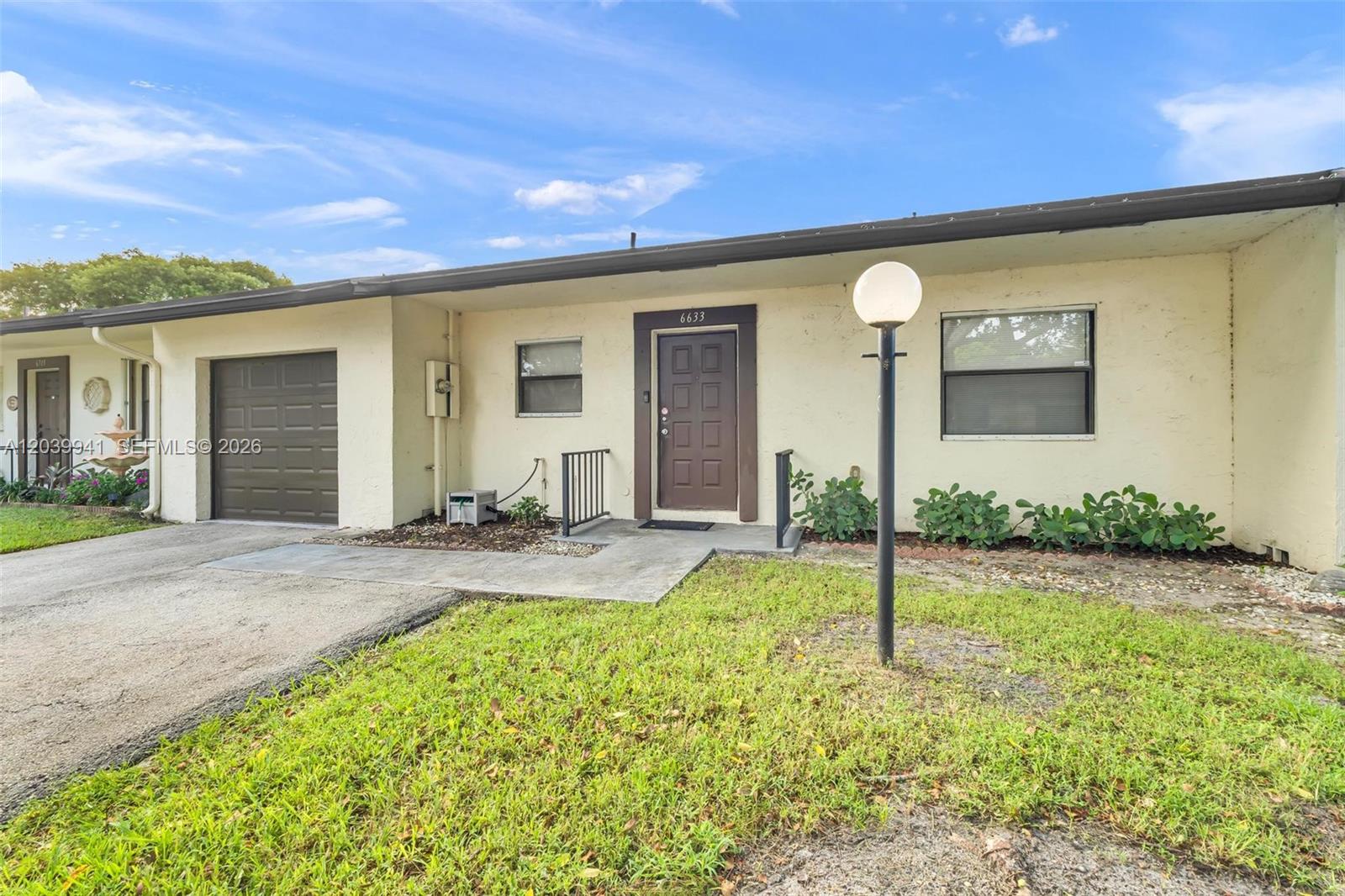 A single-story house exterior features a brown front door, a garage, and a light pole — 6633 N Parkway Dr # 7, Margate FL 33068, MARGATE, FL