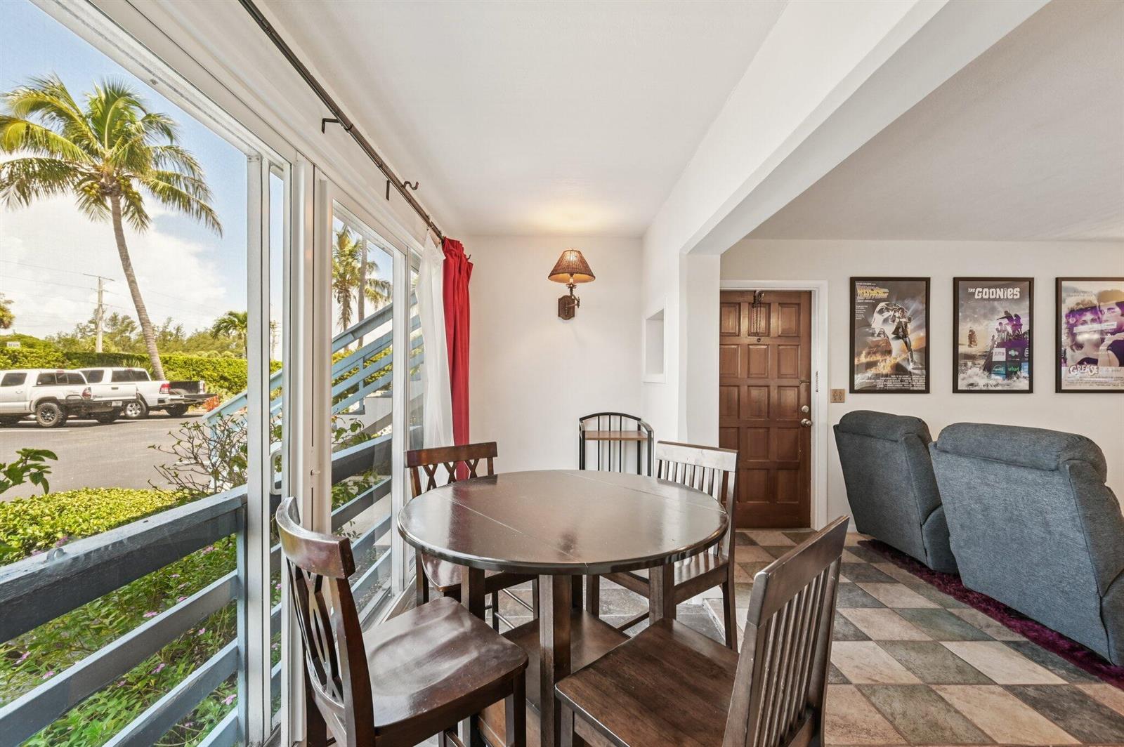 A dining area with a round wooden table, four chairs, and sliding glass doors outside — 11000 S Ocean Drive # 6, Jensen Beach FL 34957, JENSEN BEACH, FL