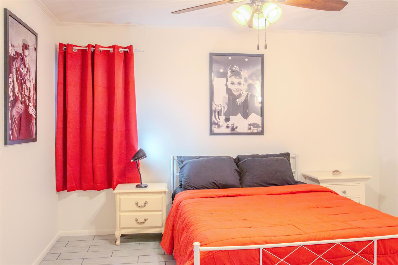 A bedroom features a bed with an orange comforter, two nightstands, and framed wall art — 11000 S Ocean Drive # 6, Jensen Beach FL 34957, JENSEN BEACH, FL