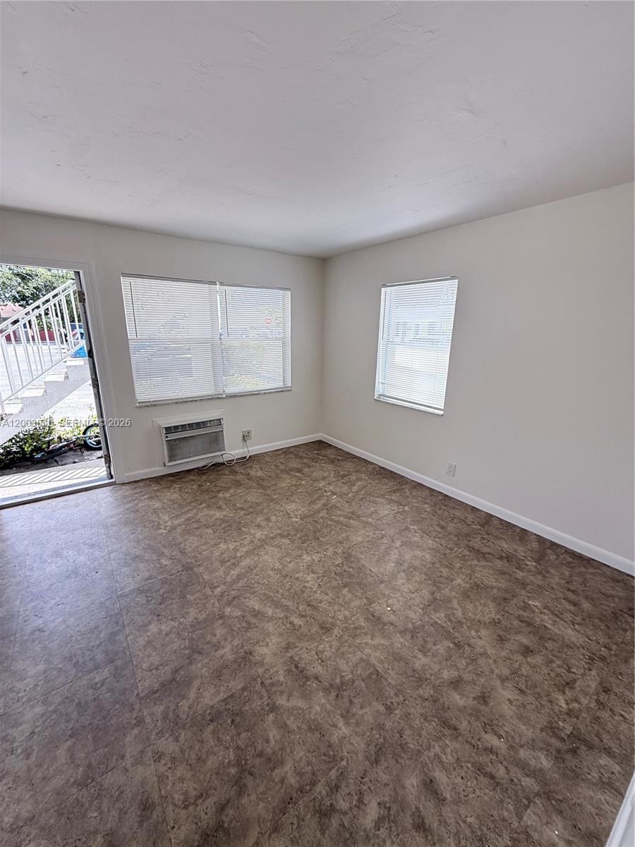An empty room features light-colored walls, brown tile flooring, two windows with blinds, and an air conditioner — 801 N H St # 1, Lake Worth FL 33460, LAKE WORTH, FL