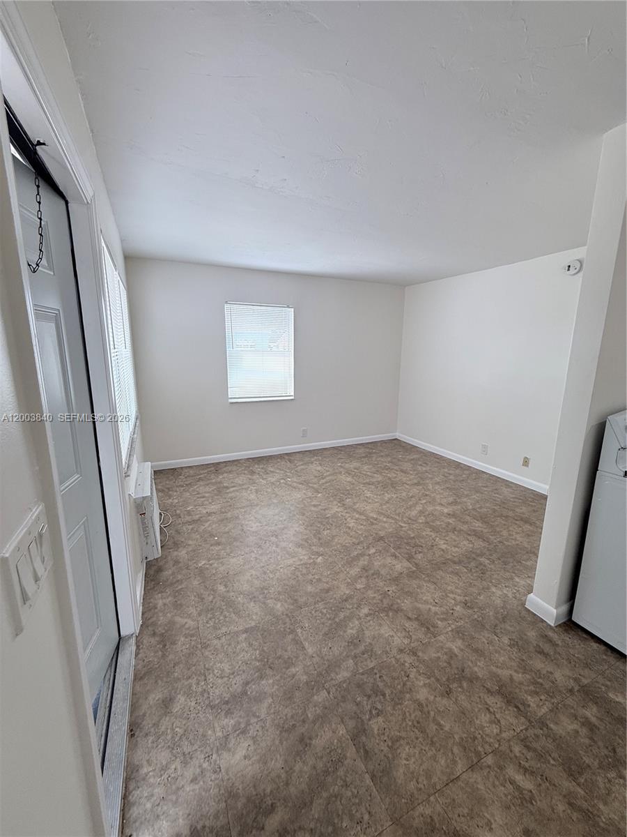 An empty room features beige walls, tile flooring, a window with blinds, and a door — 801 N H St # 1, Lake Worth FL 33460, LAKE WORTH, FL