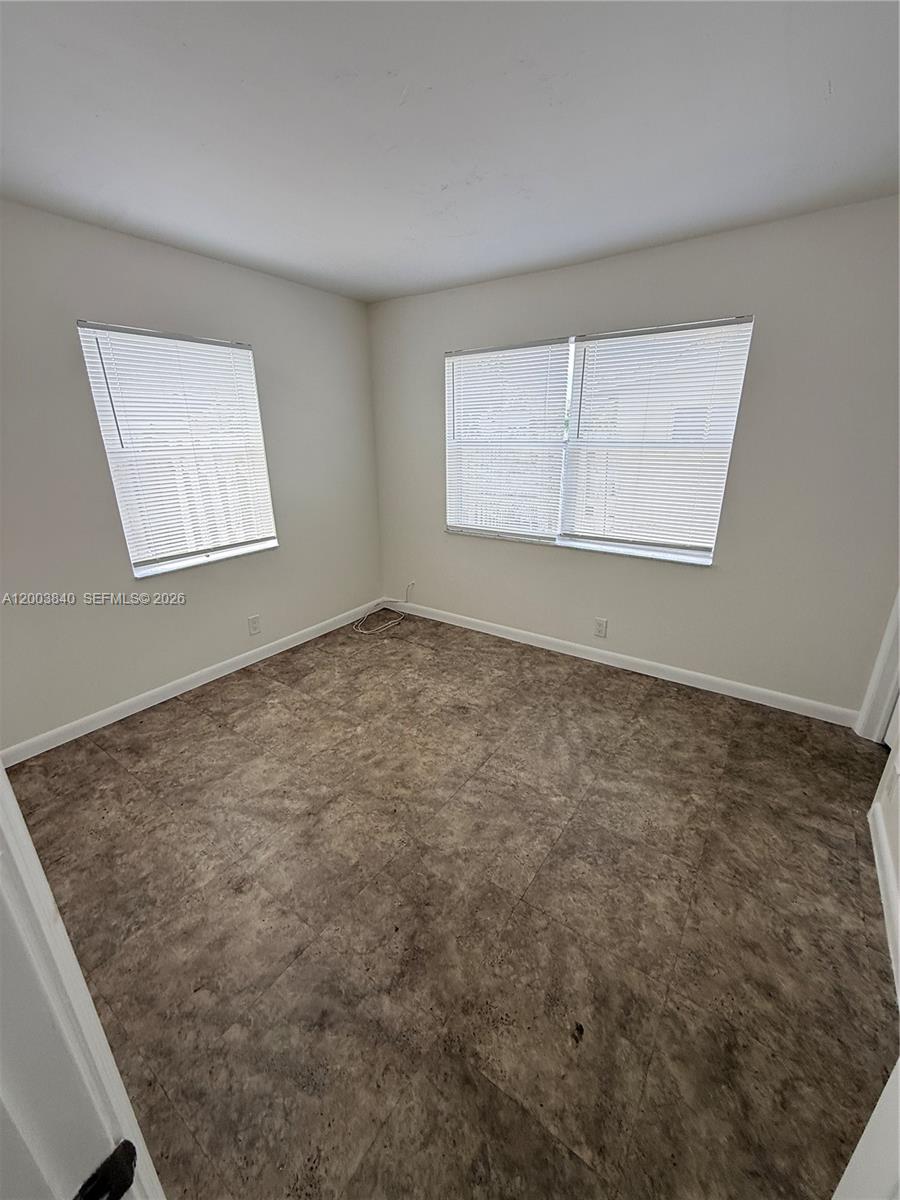 An empty room features light-colored walls, two windows with blinds, and brown tiled flooring — 801 N H St # 1, Lake Worth FL 33460, LAKE WORTH, FL
