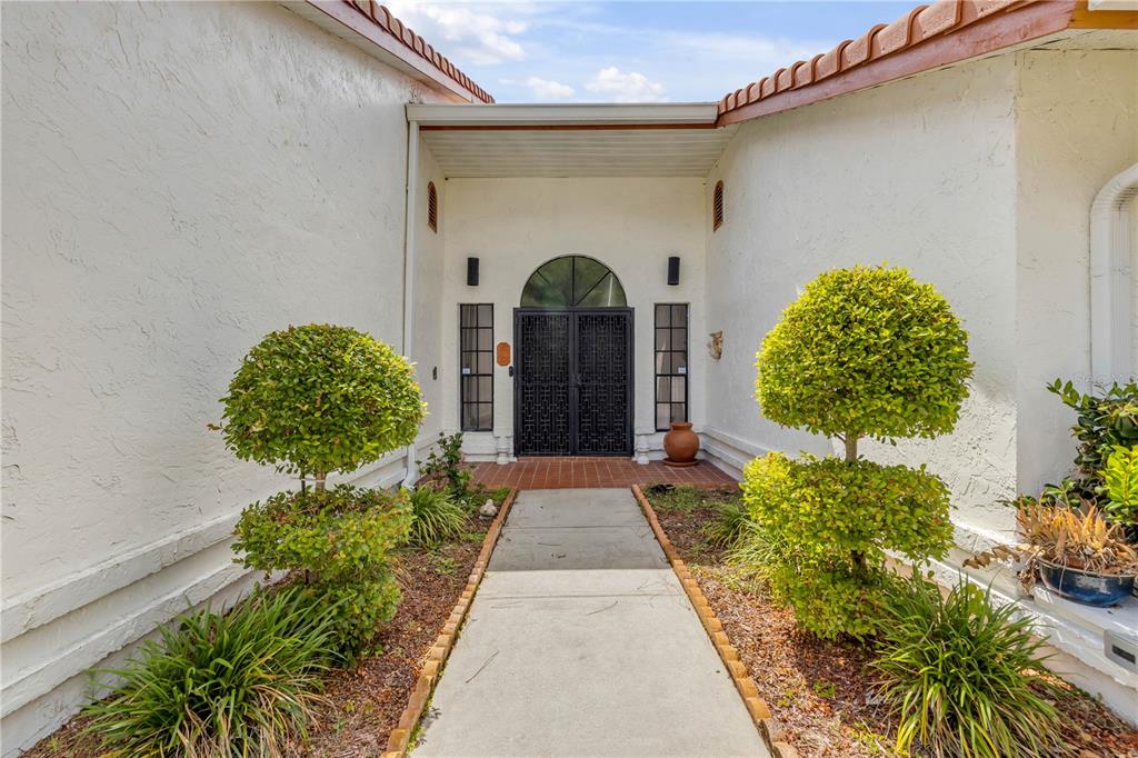 A concrete walkway leads to a front entrance with double doors and topiary shrubs — 144 MARSH WREN COURT, DAYTONA BEACH, FL