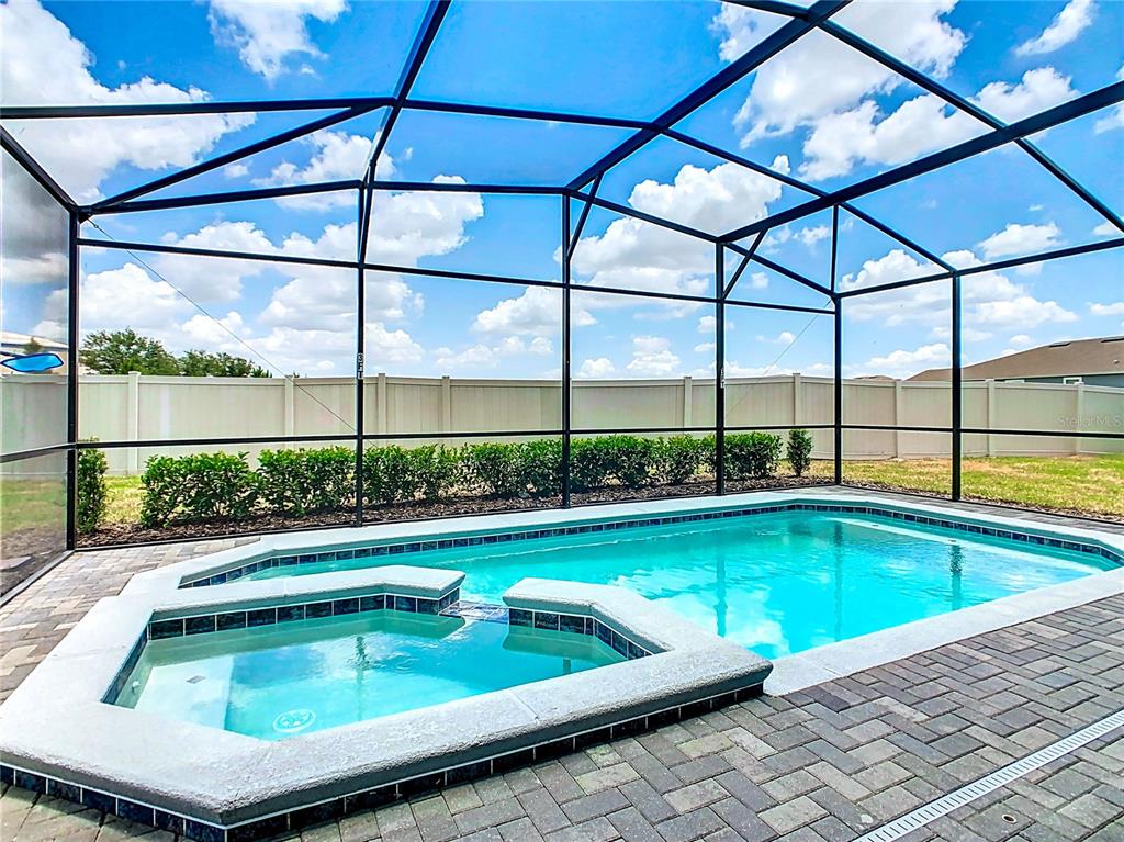 A screened-in swimming pool and spa with a brick paver deck and vinyl privacy fence — 3401 LILAC WAY, DAVENPORT, FL