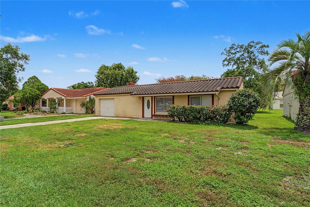 A single-story house with a tan exterior, a tiled roof, and a front-facing garage — 10145 BLUFF COURT, ORLANDO, FL