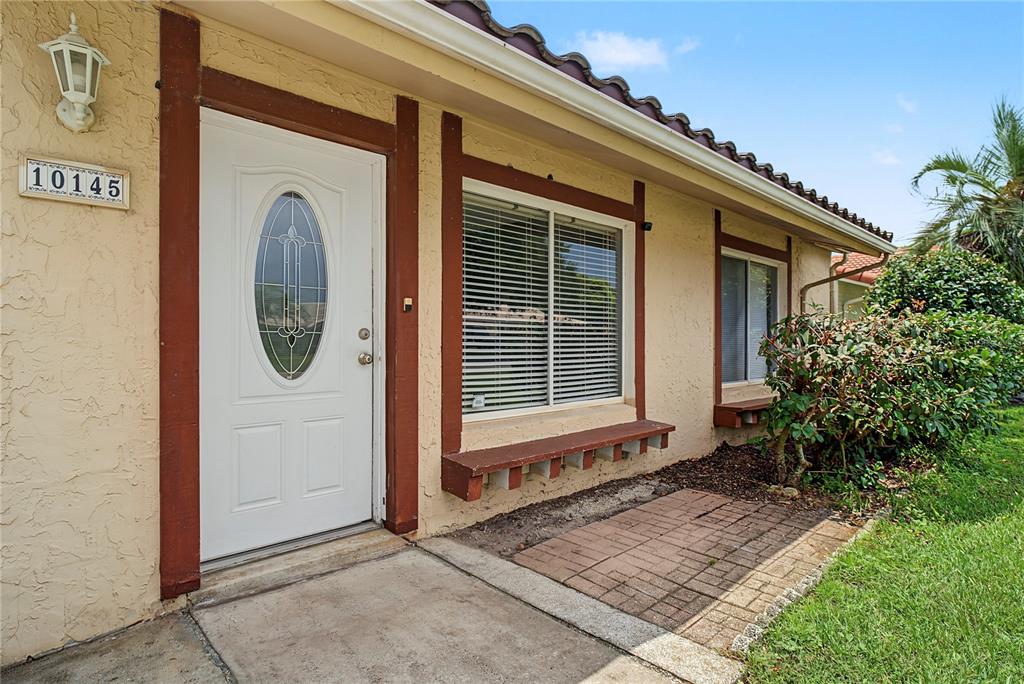 The exterior of a house features a white front door, windows with shutters, and brick pavers — 10145 BLUFF COURT, ORLANDO, FL