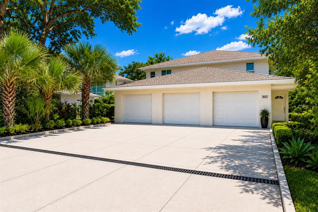 A three-car garage with a concrete driveway and landscaping in front of a house — 601 E 2ND AVENUE, NEW SMYRNA BEACH, FL