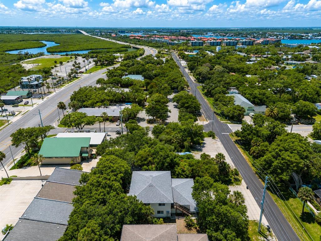 An aerial view shows a multi-story building surrounded by trees, parking lots, and nearby roads — 601 E 2ND AVENUE, NEW SMYRNA BEACH, FL