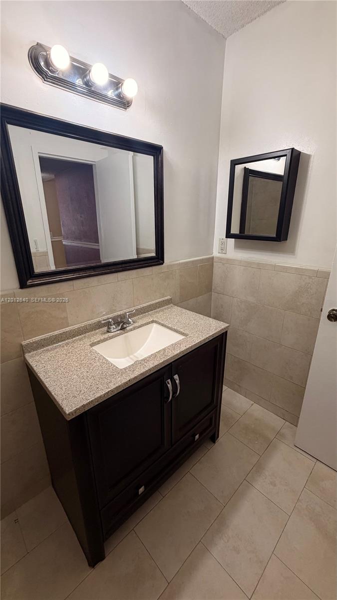 A bathroom features a dark wood vanity with a granite countertop and a wall mirror — 9972 SW 88th St # 1125, Miami FL 33176, MIAMI, FL