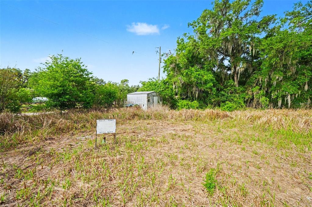 An overgrown vacant lot features a small shed and a sign indicating well pumps and tanks — 4103 STANLEY ROAD, PLANT CITY, FL