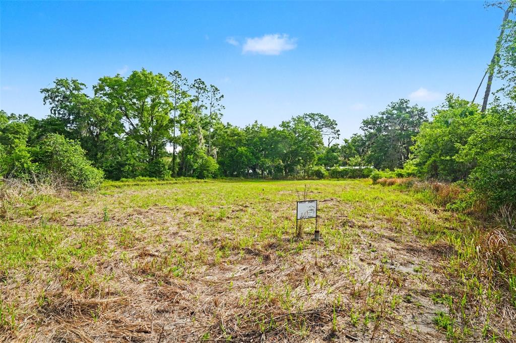 A vacant, grassy lot features a small sign and is surrounded by mature trees — 4103 STANLEY ROAD, PLANT CITY, FL
