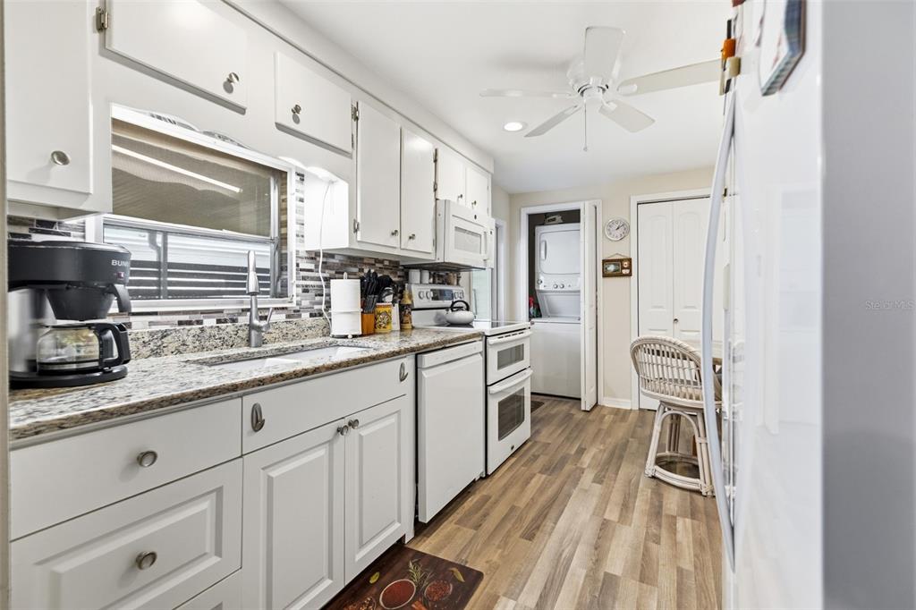 A white kitchen features granite countertops, a double oven, and a laundry closet — 5509 BERMUDA COURT, BRADENTON, FL