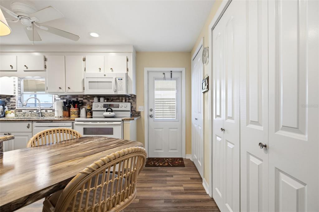 A kitchen features white cabinets, a dining table with rattan chairs, and a back door — 5509 BERMUDA COURT, BRADENTON, FL
