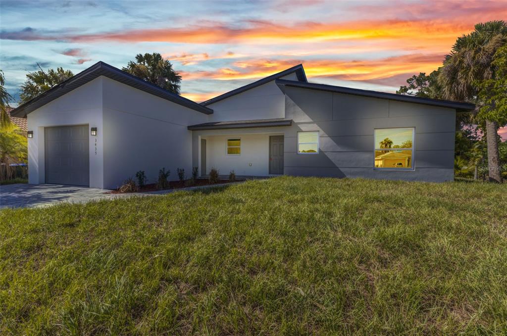 A modern single-story house with a gray garage, white and gray exterior walls, and a lawn — 3435 W PRICE BOULEVARD, NORTH PORT, FL