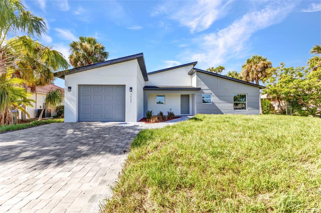 A single-story house with a gray garage, white and gray exterior, and a paved driveway — 3435 W PRICE BOULEVARD, NORTH PORT, FL
