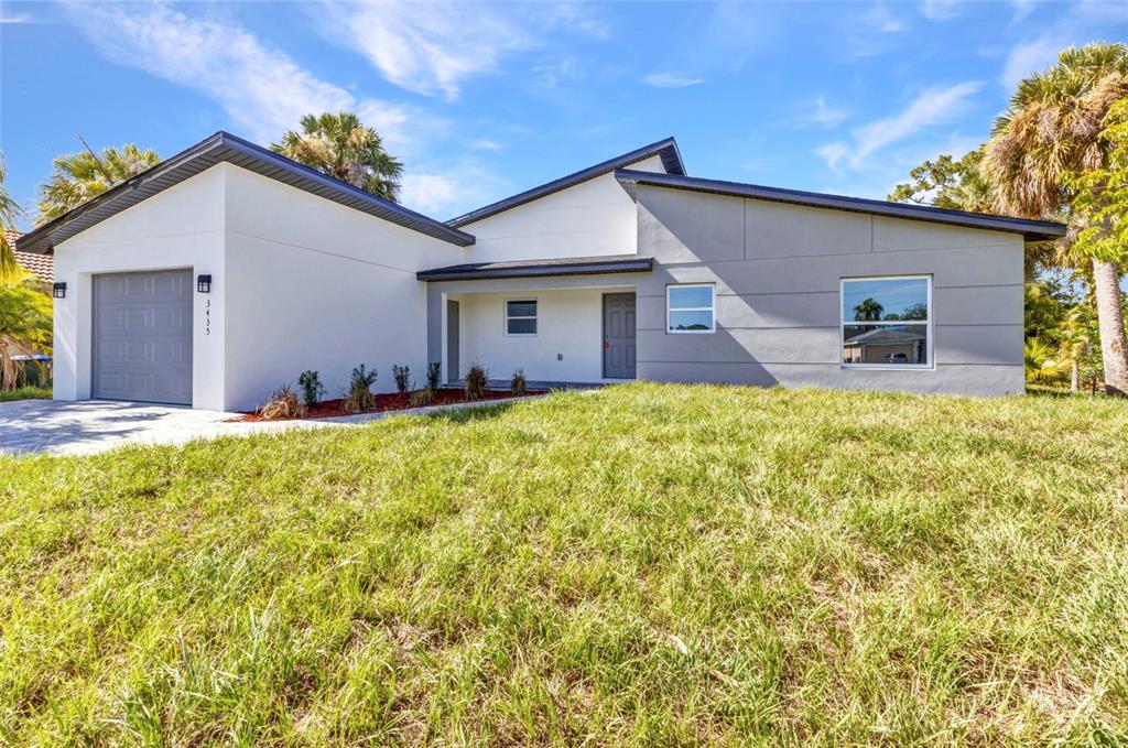 A modern single-story house with a white and gray exterior, a garage, and a lawn — 3435 W PRICE BOULEVARD, NORTH PORT, FL