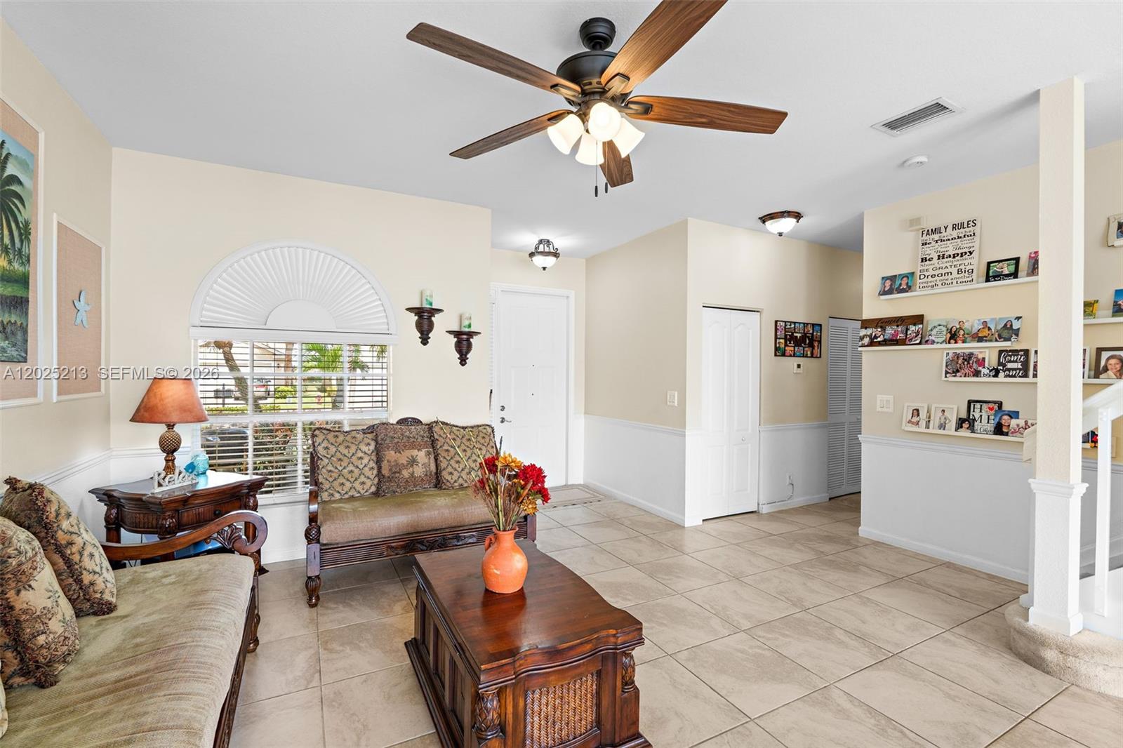 A living room features tile flooring, a ceiling fan, a wooden coffee table, and shelving — 116 Berenger Walk, Royal Palm Beach FL 33414, ROYAL PALM BEACH, FL