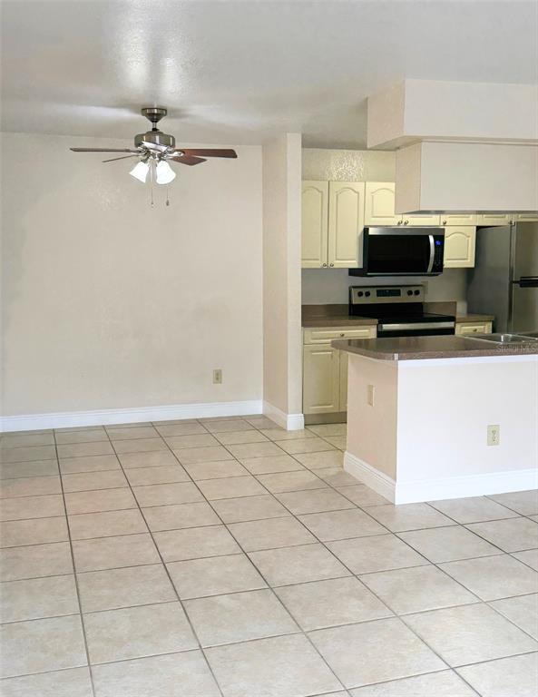 A dining area with a ceiling fan adjacent to a kitchen with light-colored cabinets — 2550 N ALAFAYA TRAIL UNIT 6202, ORLANDO, FL