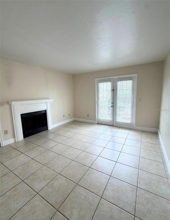 A living room features a fireplace, tile flooring, and glass doors leading to a balcony — 2550 N ALAFAYA TRAIL UNIT 6202, ORLANDO, FL