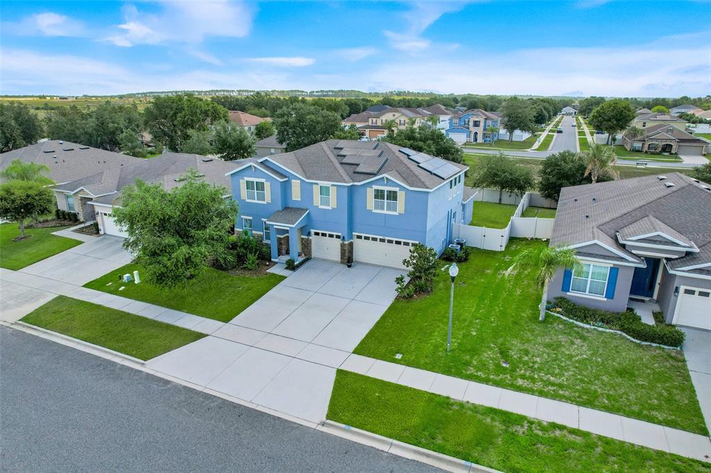 An aerial view shows a blue two-story house with a solar-paneled roof and driveway — 4516 LINWOOD TRACE LANE, CLERMONT, FL