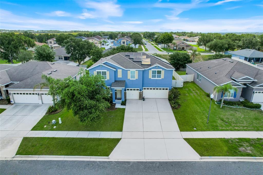 An aerial view of a two-story blue house with a driveway and solar panels — 4516 LINWOOD TRACE LANE, CLERMONT, FL