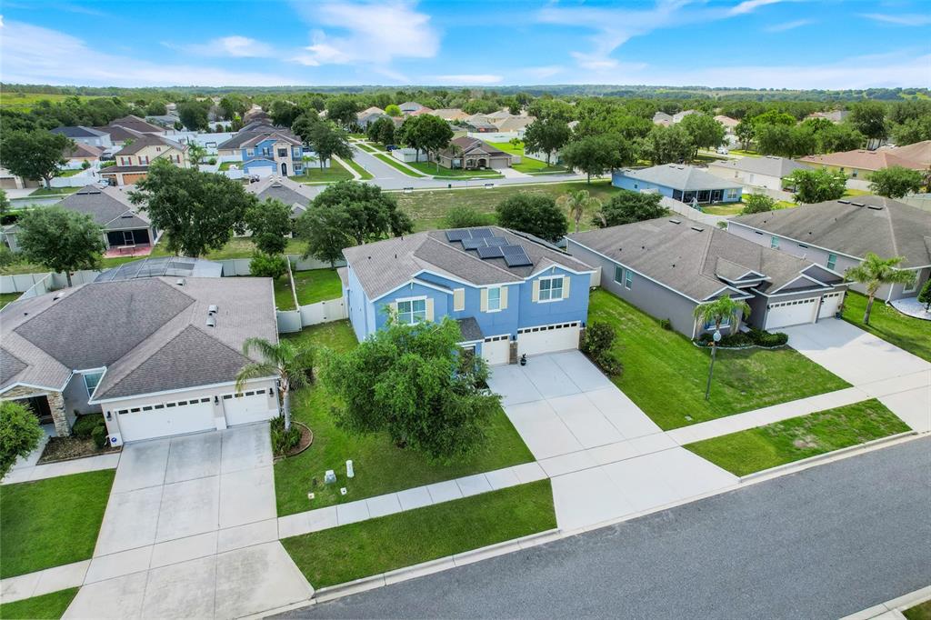 An aerial view shows a blue two-story house with solar panels and a concrete driveway — 4516 LINWOOD TRACE LANE, CLERMONT, FL