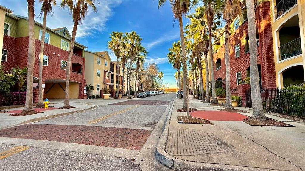 A street view of apartment buildings with palm trees and a brick-paved crosswalk — 1810 E PALM AVENUE UNIT 5114, TAMPA, FL