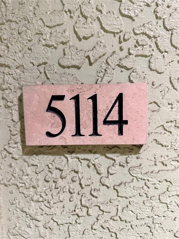 A rectangular sign with the number 5114 is mounted on a textured beige wall — 1810 E PALM AVENUE UNIT 5114, TAMPA, FL