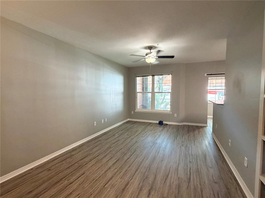 An empty living room features light gray walls, wood-look flooring, and a ceiling fan — 1810 E PALM AVENUE UNIT 5114, TAMPA, FL