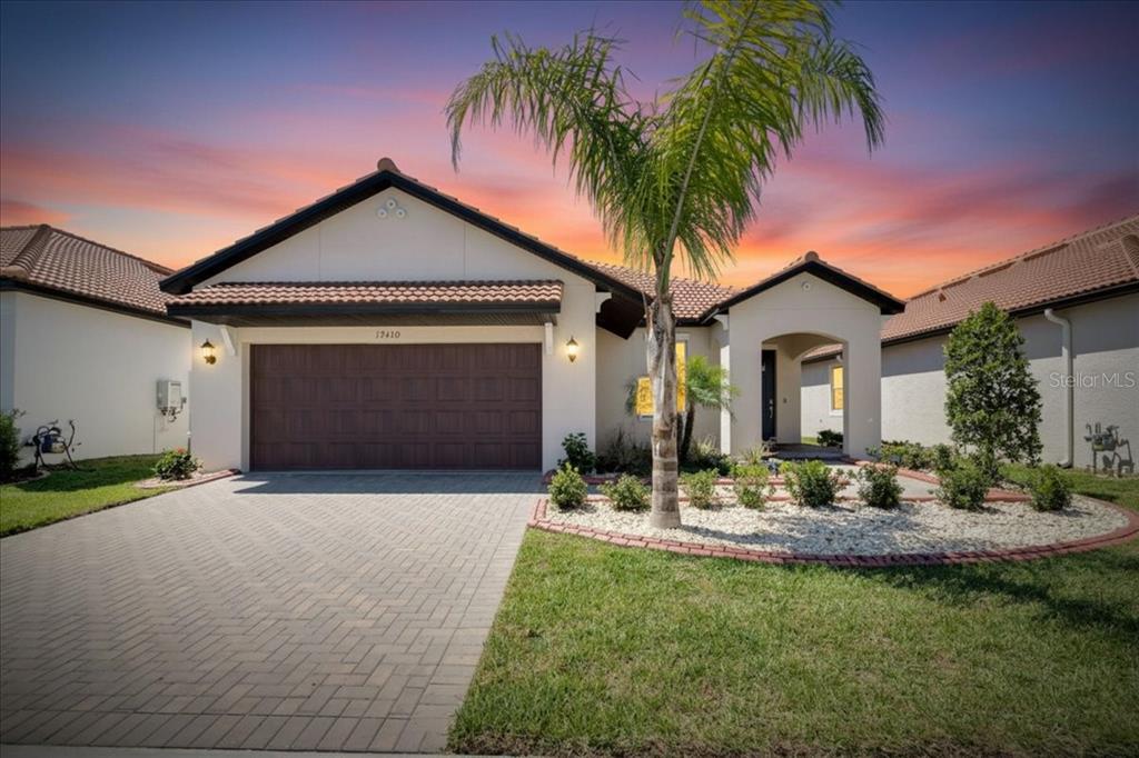 A single-story house with a tiled roof, a two-car garage, and a palm tree — 17410 HOLLY WELL AVENUE, WIMAUMA, FL