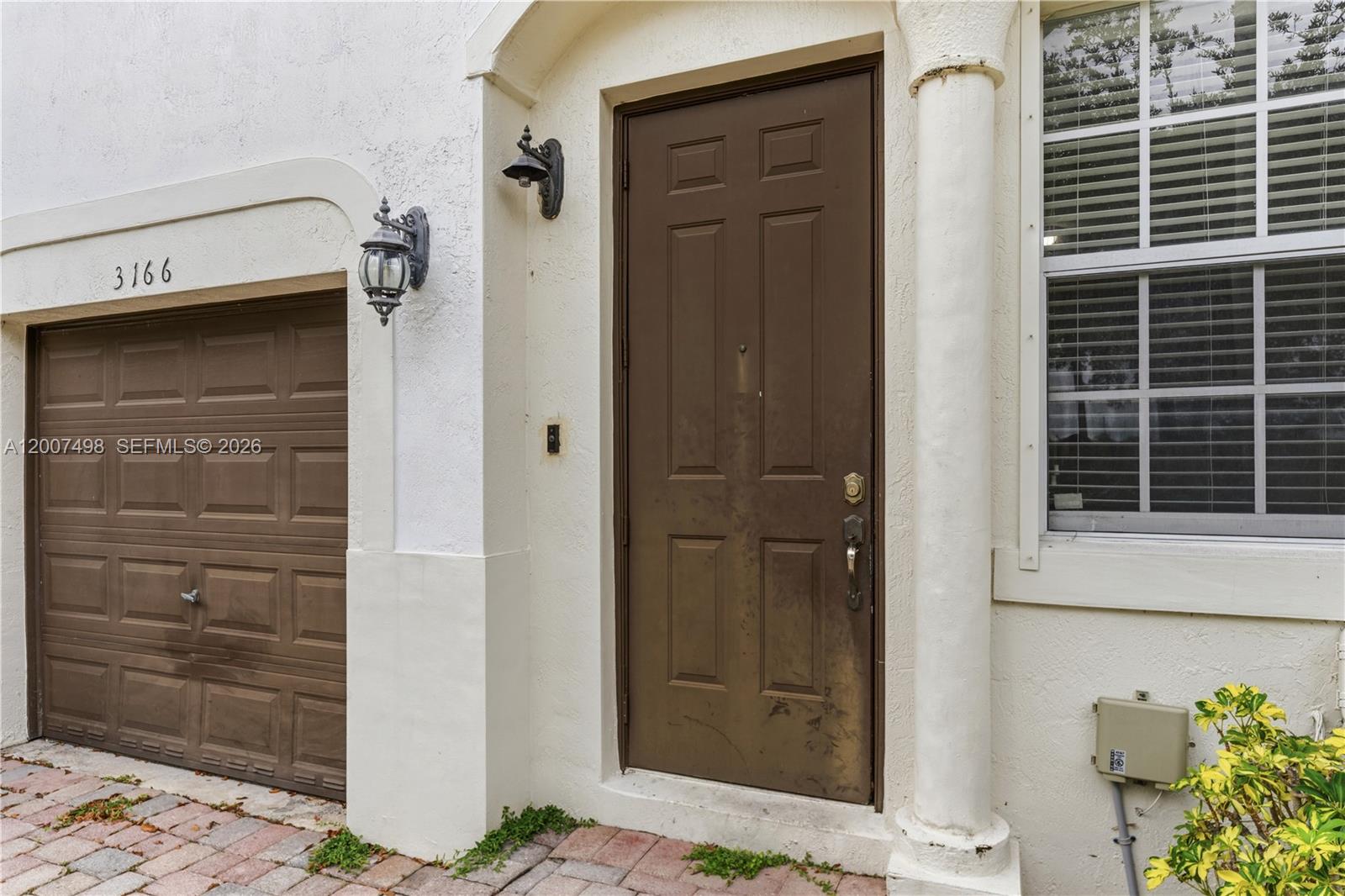 The exterior of a home features a brown garage door, a matching front door, and columns — 3166 NE 11th St, Homestead FL 33033, HOMESTEAD, FL