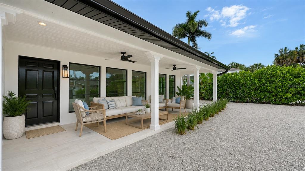 A covered patio features white columns, outdoor furniture, and a gravel yard — 1041 INDIAN BEACH DRIVE, SARASOTA, FL