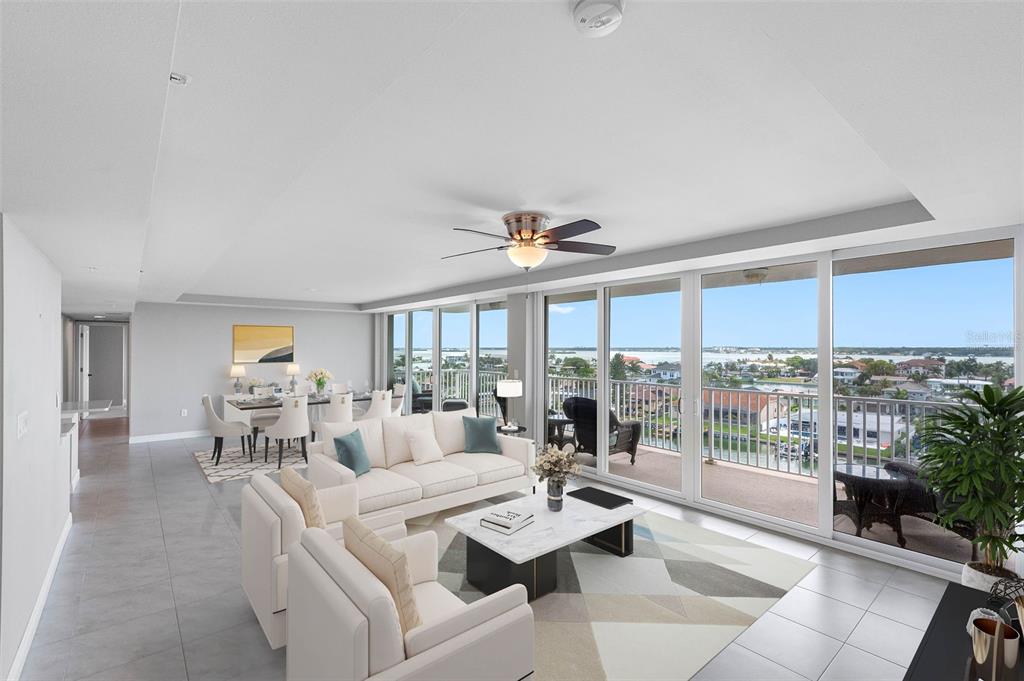 A bright living and dining area with tile floors, white furniture, and a balcony view — 223 ISLAND WAY UNIT 7F, CLEARWATER BEACH, FL