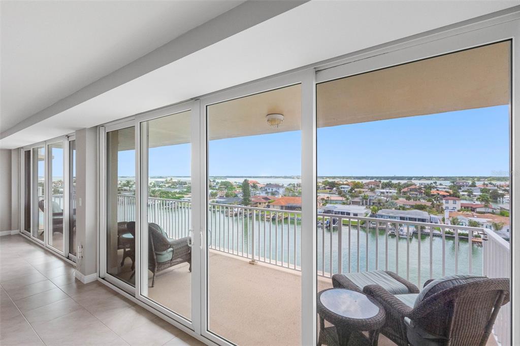 A room with large sliding glass doors opening onto a balcony overlooking a waterfront neighborhood — 223 ISLAND WAY UNIT 7F, CLEARWATER BEACH, FL