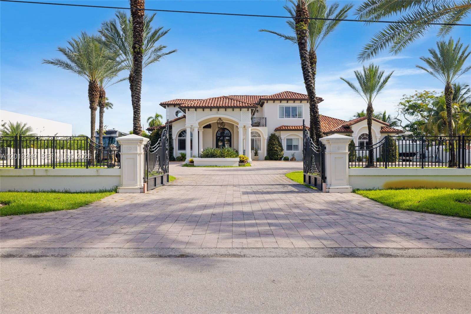 A two-story Mediterranean-style house with a gated driveway and palm trees in the front yard — 9861 NW 135th St, Hialeah Gardens FL 33018, HIALEAH GARDENS, FL